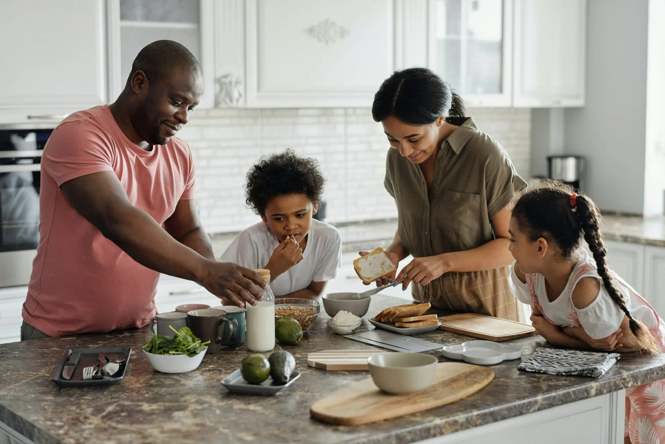 Family of four, including two adults and two children, preparing food in a kitchen.