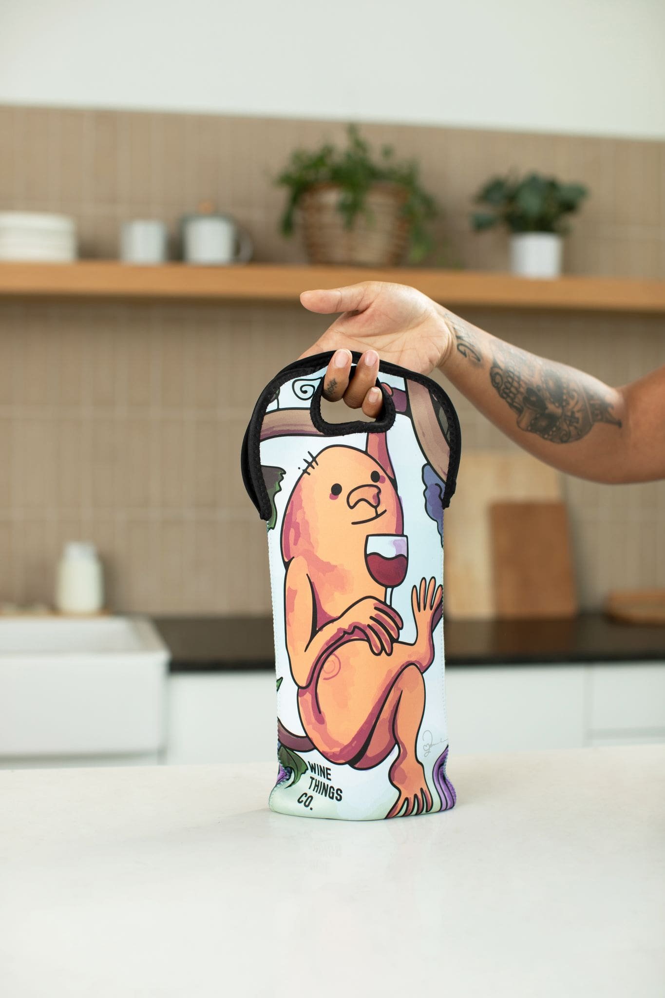 person holding up Insulated wine tote with orange wine monster illustration