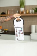 A person holding a Safi Marketplace wine tote bag in front of a kitchen.