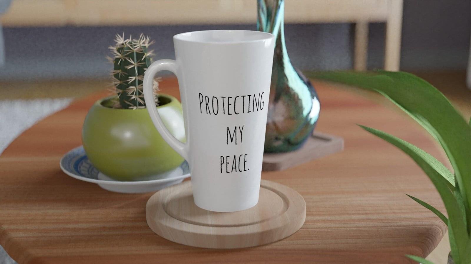 White ceramic mug with the phrase 'Protecting My Peace' printed on it, placed on a wooden surface.